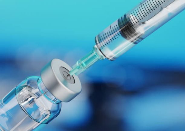 istockphoto-1304499871-612×612 Medical disposable syringe for vaccine injection and glass vial on blue blur background.
