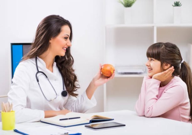 Female doctor showing apple to a little girl at the medical office. Female doctor showing apple to a little girl at the medical office.