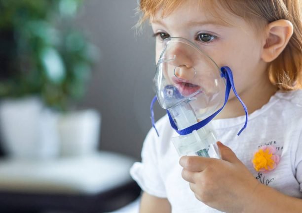 Cute toddler girl are sitting and holds a nebulizer mask leaning against the face, concept airway treatment Cute toddler girl are sitting and holds a nebulizer mask leaning against the face, concept airway treatment.